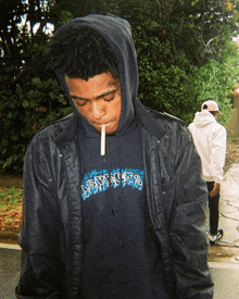 a man wearing a black jacket and a hoodie with the word sns on it