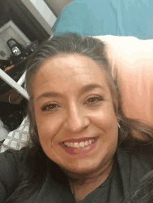 a woman laying on a bed smiling with a pink pillow in the background