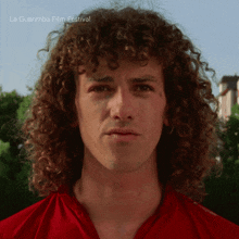 a man with curly hair is standing in front of a sign that says la guarimba film festival on it