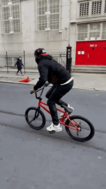 a man is riding a red bike on a street in front of a building with exit 3 on it