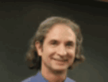 a blurry picture of a man with long hair smiling