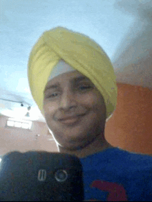 a man wearing a yellow turban smiles while taking a selfie