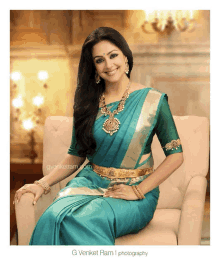 a woman wearing a blue saree and gold jewelry is sitting on a couch