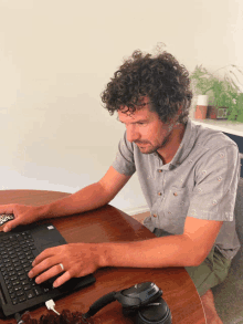 a man sits at a table with a laptop and headphones on the table