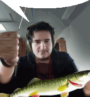 a man wearing headphones is holding a large fish in his hands