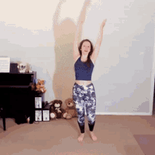 a woman is standing with her arms in the air in a room with stuffed animals and a piano .