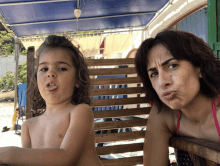 a woman making a funny face next to a child who is sticking his tongue out