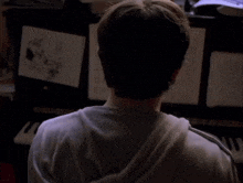 a man in a white hoodie is playing a piano in a dark room
