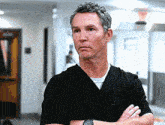 a man wearing a black scrub top with his arms crossed