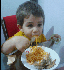 a young boy is eating spaghetti with a fork and knife