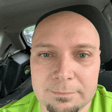 a man wearing a green shirt and a black hat is sitting in the back seat of a car