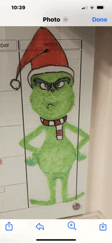 a phone screen shows a drawing of a grinch with a santa hat