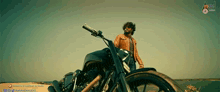 a man in a leather jacket is riding a motorcycle on the beach