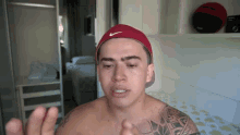 a shirtless man wearing a red nike hat is making a funny face .