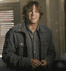a man wearing a denim jacket and a button up shirt is smiling