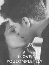 a man and a woman are kissing in a black and white photo and the man is saying `` i love you completely '' .