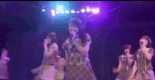 a woman is singing into a microphone on a stage with other women .