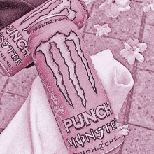 a pink monster energy drink is sitting on top of a white towel on a table .