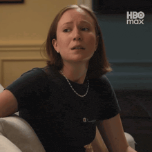 a woman is sitting on a couch with a hbo max logo in the background