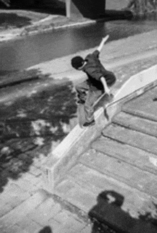 a black and white photo of a person riding a skateboard down a railing .