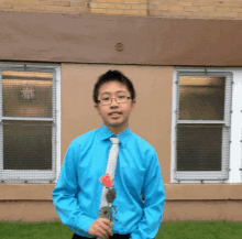 a man in a blue shirt and tie is holding a rose