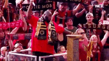 a man in a red shirt stands in front of a crowd holding a trophy and a sign that says fox 17