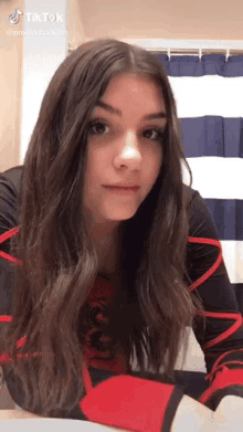 a young girl with long hair is sitting in front of a shower curtain .