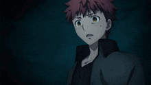 a man with red hair and a black jacket is looking at something in the dark