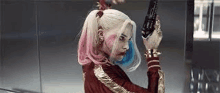 a woman in a harley quinn costume is holding a gun in her hand .