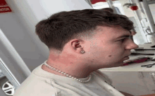 a man wearing a pearl necklace is getting his hair cut in a salon