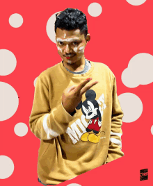 a man wearing a mickey mouse sweatshirt with white paint on his face giving the middle finger