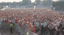 a crowd of people standing in front of a fence with a sign that says ' stadium ' on it