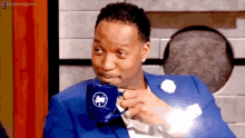 a man in a blue suit is drinking from a blue mug with a bird on it .