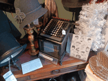 an old fashioned calculator sits on a wooden table next to a hat