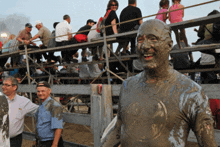 a man covered in mud is smiling in front of a crowd of people