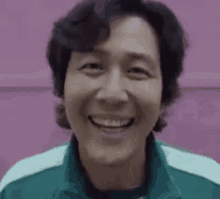 a close up of a man smiling in front of a pink background .