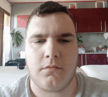 a man making a funny face in front of a kitchen with red cabinets