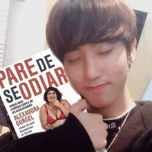 a young man is holding a book that says parede seodiar .