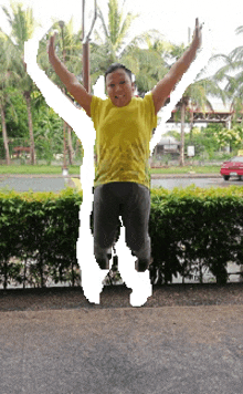 a man in a yellow shirt jumps in the air with his arms outstretched