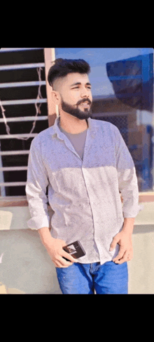 a man with a beard is standing in front of a window