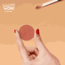 a woman with red nails is holding a makeup brush over a circle that says beauty wow on the bottom