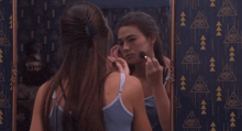 a woman applying makeup in front of a mirror with an eye on the wall