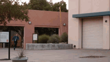 a man walking in front of a building that has a sign that says ' texas a & m college ' on it