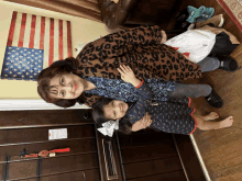 a woman in a leopard print jacket holds a little girl