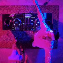 a man is doing a handstand in front of a dj controller in a neon room .