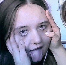 a woman sticking her tongue out with her hands on her face