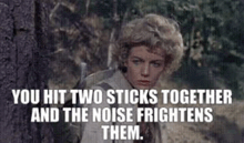 a woman is standing next to a tree in the woods holding a gun and a quote from a movie .