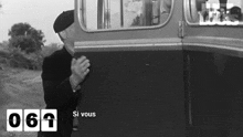 a black and white photo of a man standing next to a bus with a sign that says `` si vous '' .