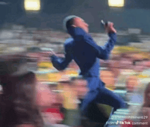 a man in a blue suit is singing into a microphone in front of a crowd ..