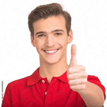 a young man in a red shirt is smiling and giving a thumbs up sign